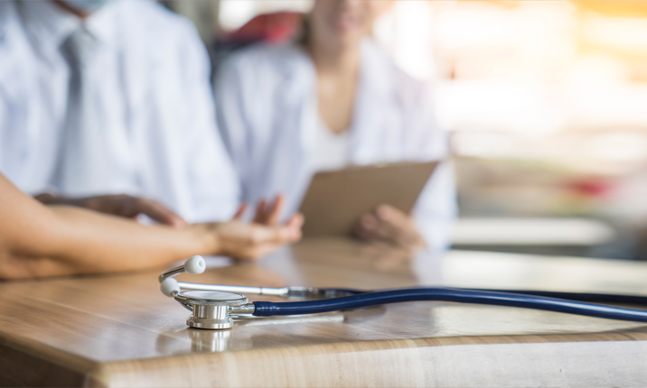 Close Stethoscope on Table Blurred Doctor