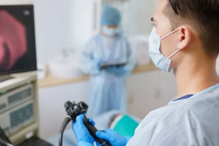 A doctor holding a medical device to prepare for a colonoscopy