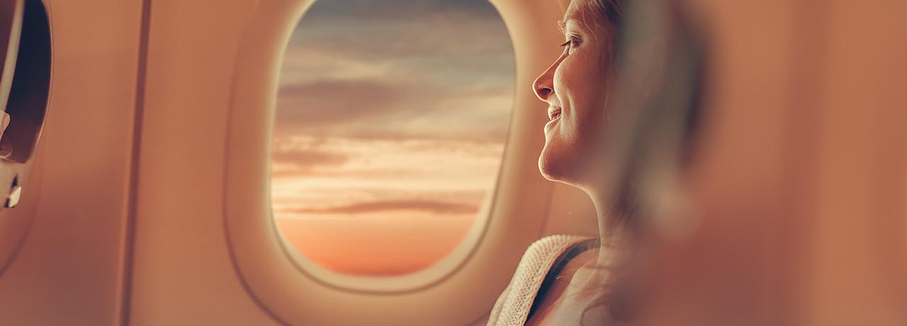 Frau blickt aus dem Fenster eines Flugzeugs