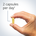 Hand holding a Immune Active™ capsule, indicating a recommended dosage of two capsules per day for immune support.