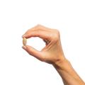 Hand holding a single Metagenics Serenagen® tablet. 