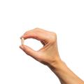 Hand holding a single Metagenics SpectraZyme® Complete capsule. 