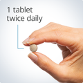 Hand holding a small tablet, indicating a recommended dosage of one tablet twice daily for PMS support.