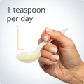 Hand holding a teaspoon of Metagenics OmegaGenics® Fish Oil EPA-DHA Liquid 2400 mg