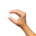 A woman's hand holding a single capsule - Metagenics™ UltraFlora® BiomePro (Serving Size: 1 Capsule)