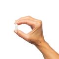 Hand holding a single Bone Builder® tablet.