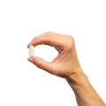 Woman’s hand holding Metagenics Fibroplex® tablet.