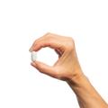 Woman’s hand holding Metagenics ChondroCare® tablet.
