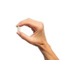 Woman’s hand holding Metagenics Collagenics® tablet.