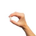 Hand holding a single Metagenics Vasotensin® tablet. 