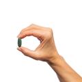 Woman’s hand holding Metagenics Multigenics® Multivitamin tablet.