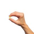 Woman’s hand holding Metagenics OmegaGenics® Evening Primrose Oil softgel. 