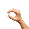 Woman’s hand holding Metagenics Cortico-B5B6® tablet.