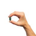 Woman’s hand holding Metagenics Multigenics® Multivitamin with Iron tablet.