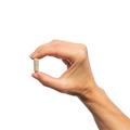 Woman’s hand holding Metagenics Fenugreek Plus® capsule. 