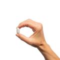 Hand holding a single Metagenics SpectraZyme® Pancreatic Enzymes Extra Strength tablet. 
