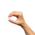 Hand holding a single Metagenics MyoCalm® tablet. 