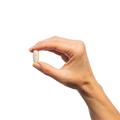 Hand holding a single Metagenics OsteoVantiv®, tablet.  