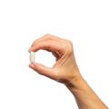Woman’s hand holding Metagenics GlutaClear® tablet.