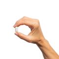 Hand holding a single Metagenics SpectraZyme Betaine HCI + Pepsin tablet. 