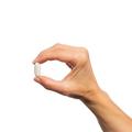 Hand holding a single Bone Builder® Extra Strength tablet.