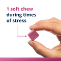 Hand holding a Metagenics HerWellness™ Rapid Stress Relief soft chews with the text '1 soft chew during times of stress' to convey supplement dosage.
