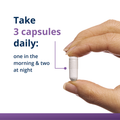 Hand holding magnesium capsule with instructions to take 3 daily—1 in morning and 2 at night for brain health support