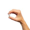 Woman’s hand holding Metagenics HerSynergy® tablet.