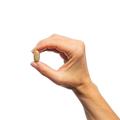Woman’s hand holding Metagenics Fem EstroPlex® tablet.