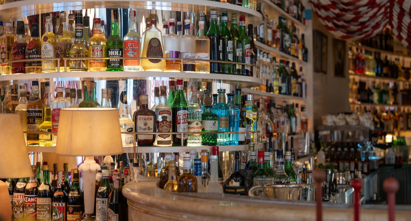 Alcuni ripiani del bar nel ristorante Splendido con una vasta selezione di liquori, messa in risalto da un’illuminazione avvolgente e da elementi decorativi.