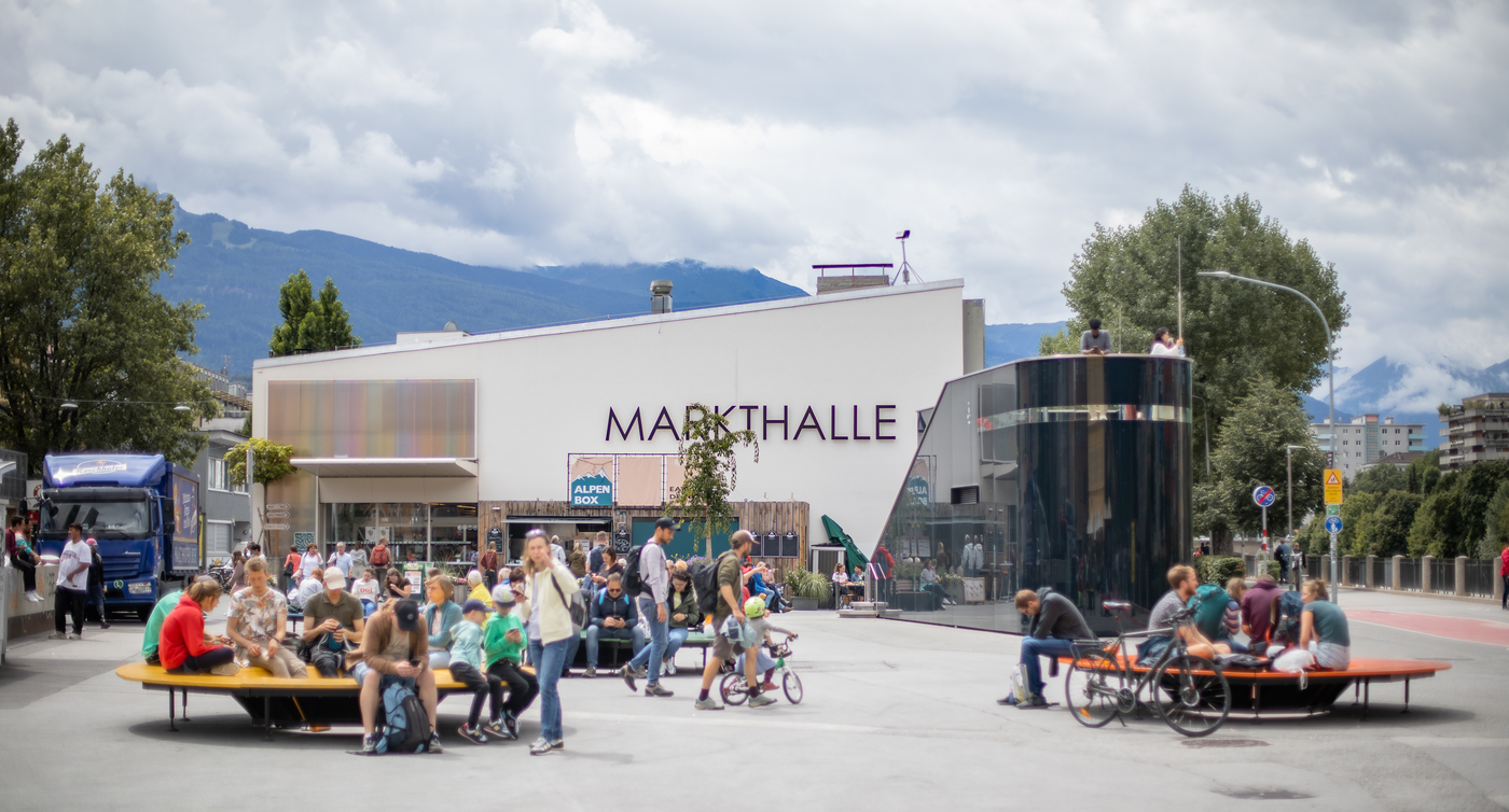 Persone sedute su panchine in Marktplatz, davanti alla Markthalle.
