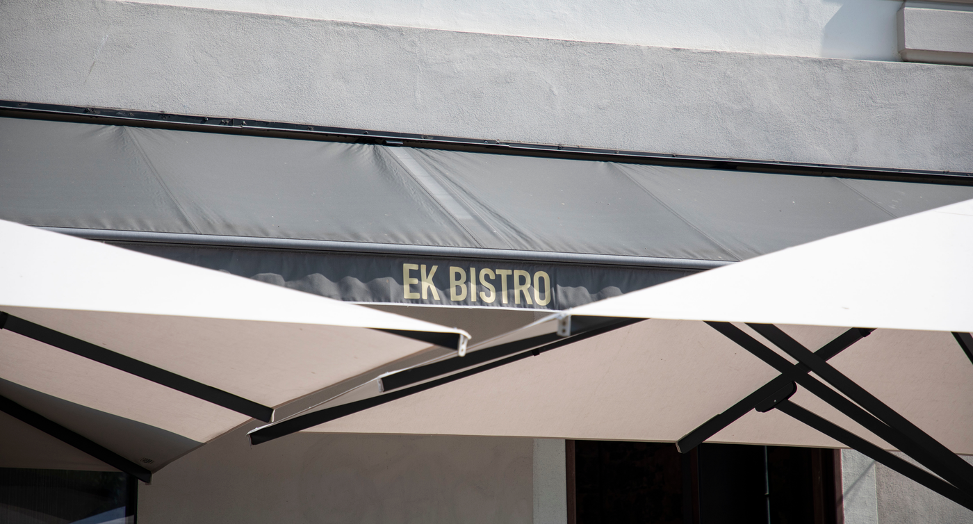 Offene Terrassenschirme und die Restaurantbeschriftung Ek Bistro.
