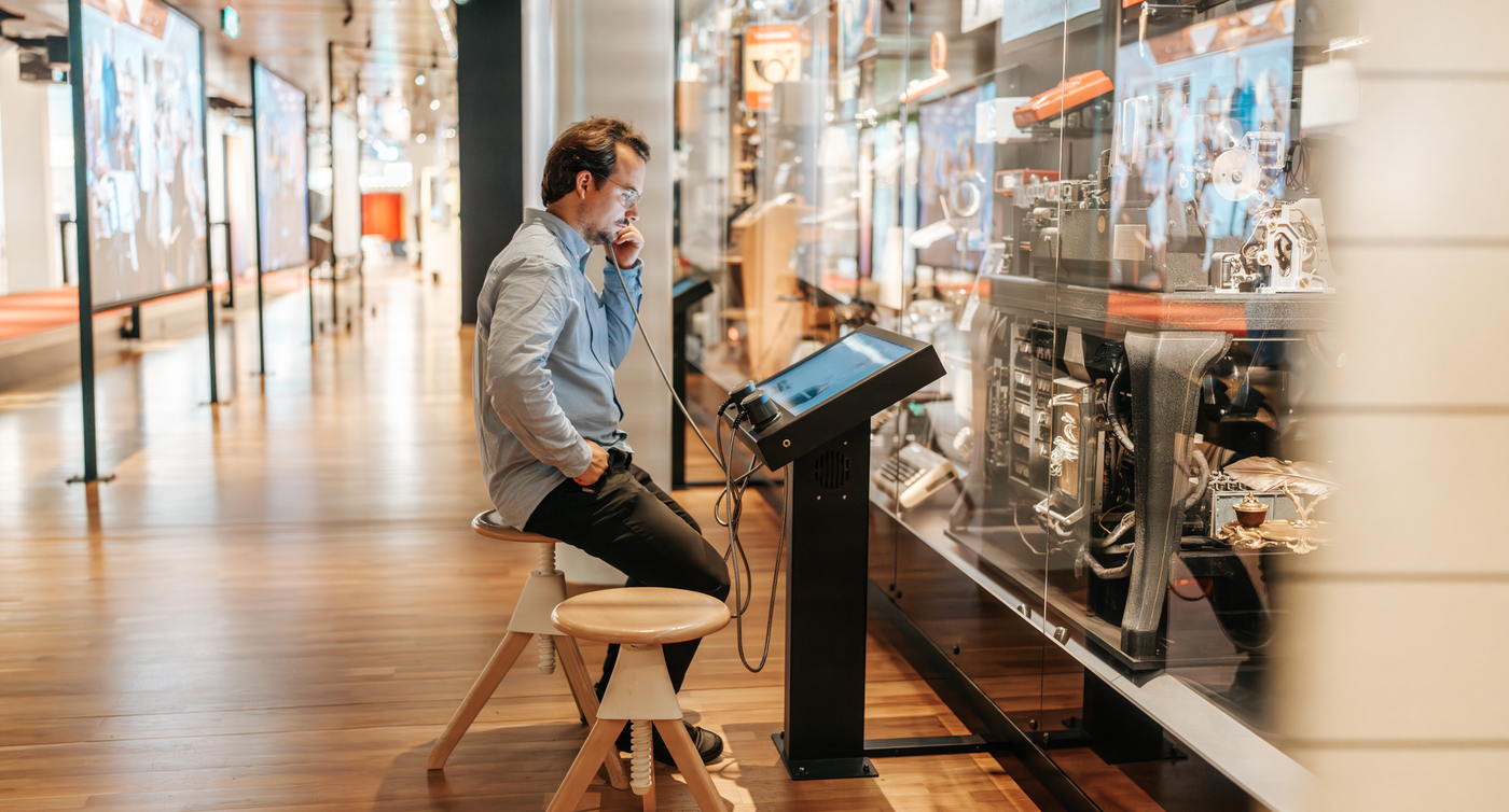 Un homme est assis dans un musée et écoute dans un écouteur à l'ancienne.