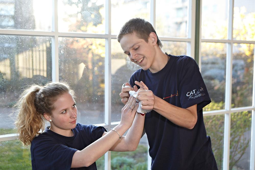 A young volunteer from the Samaritan Youth bandages a colleague's hand.