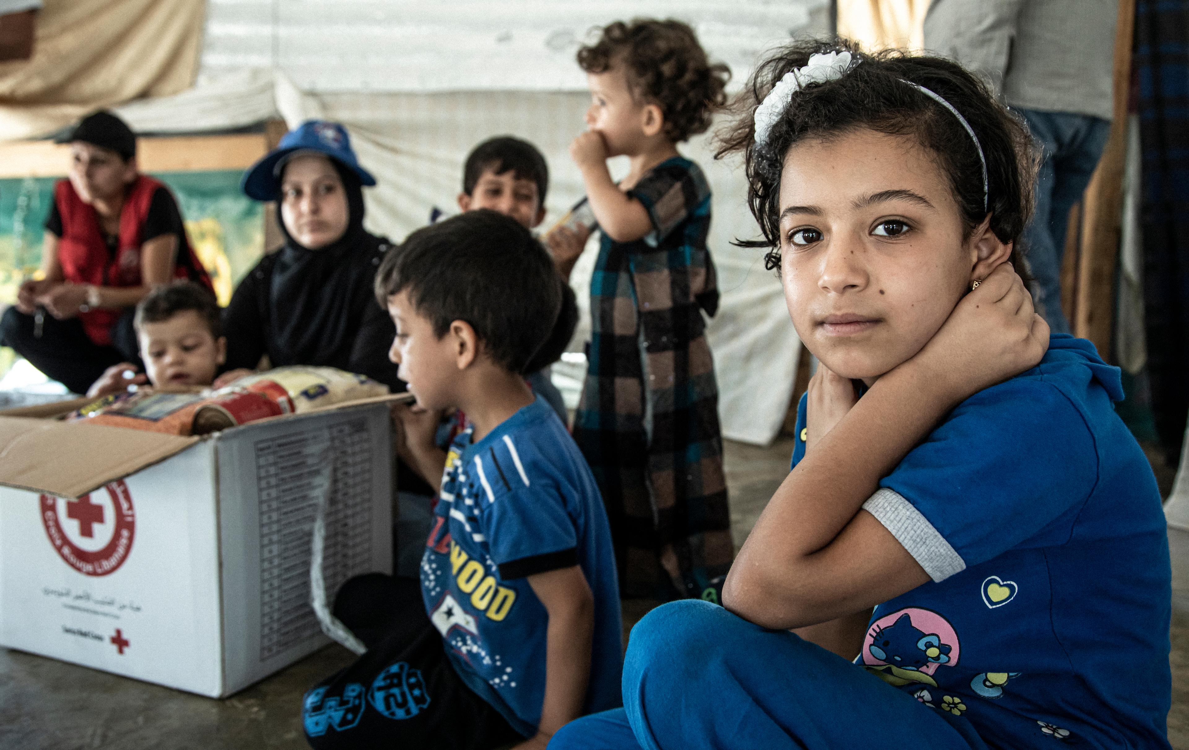 Inass (im Vordergrund) und ihre Familie freuen sich auf das monatliche Lebensmittelpaket des Roten Kreuzes. Flüchtlingslager in der Region Akkar im Norden von Libanon.