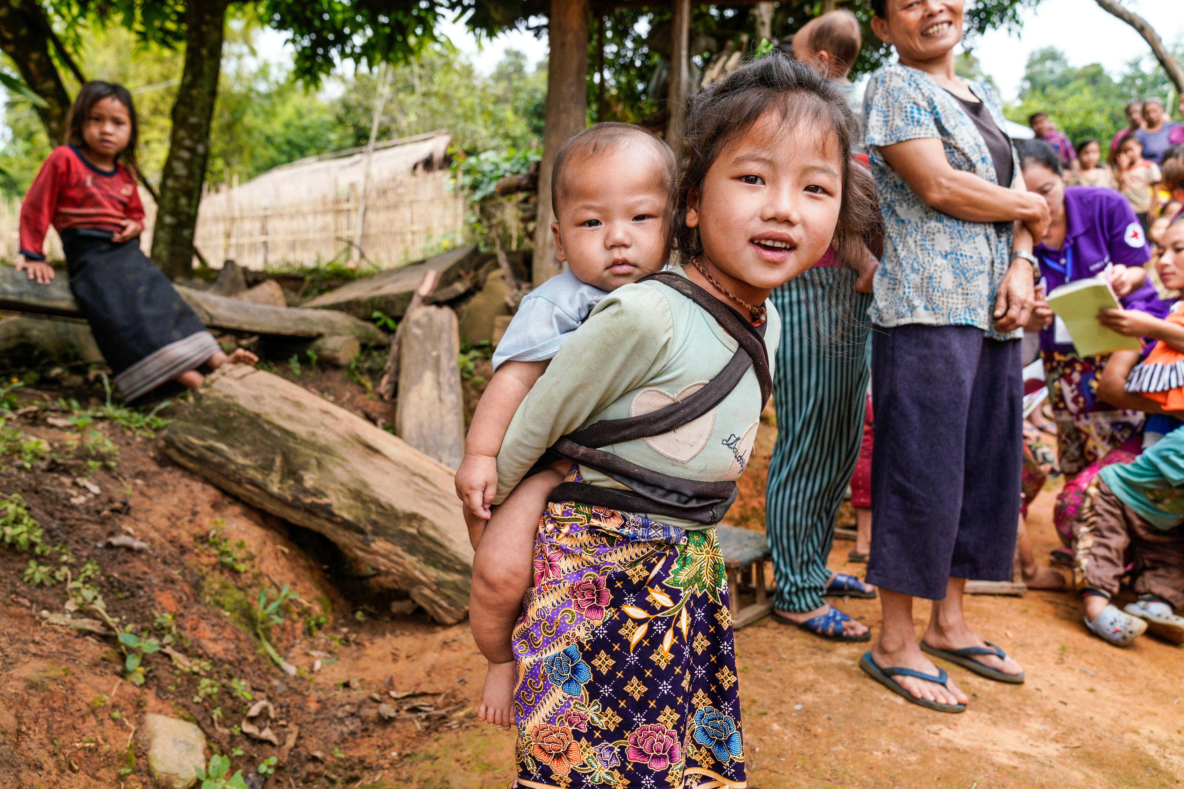 Dans le village de Chompet District, province de Luang Prabang au Laos, une jeune fille porte un bébé dans son dos.