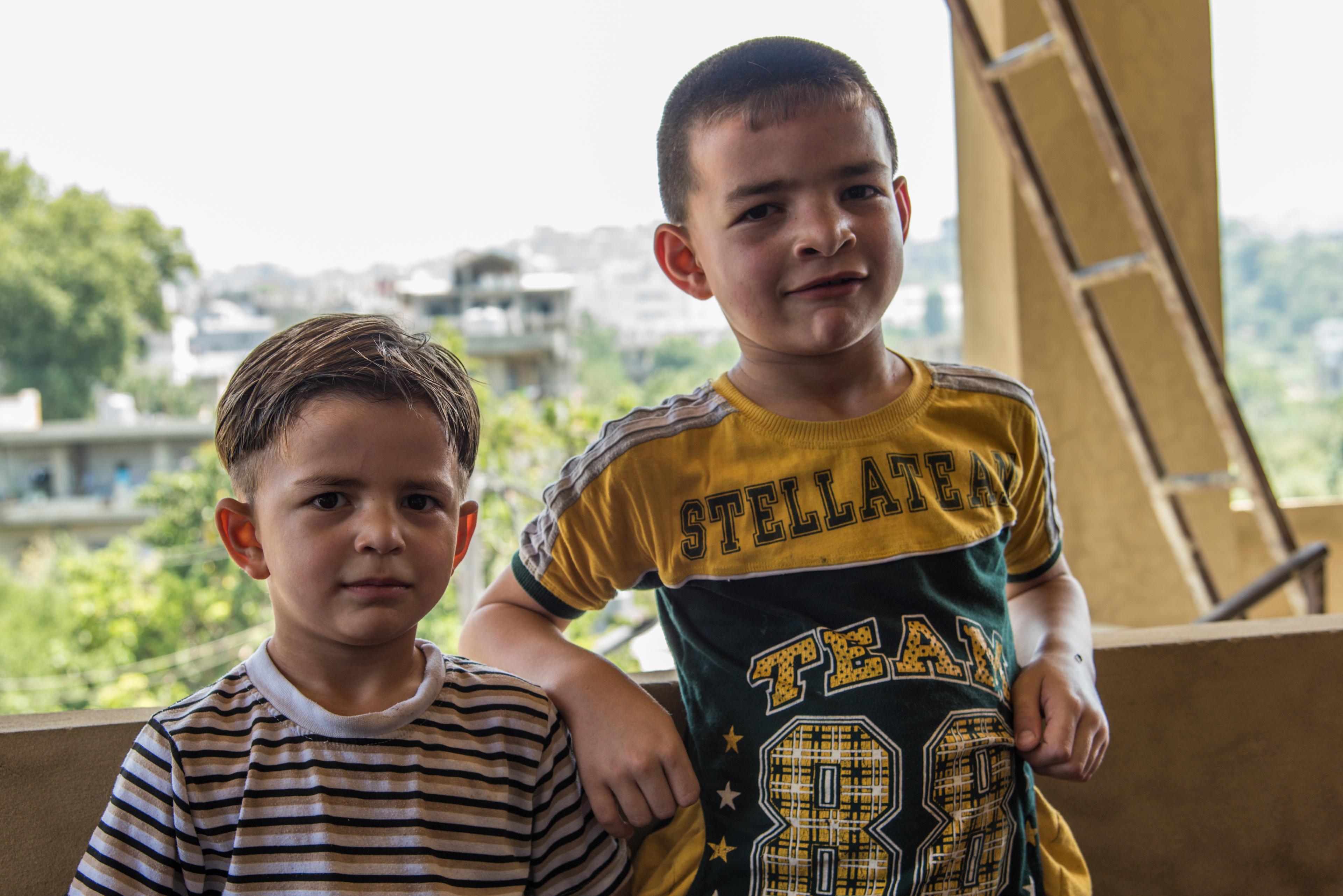 Deux garçons des familles sur le balcon, tous deux avec un sourire discret.