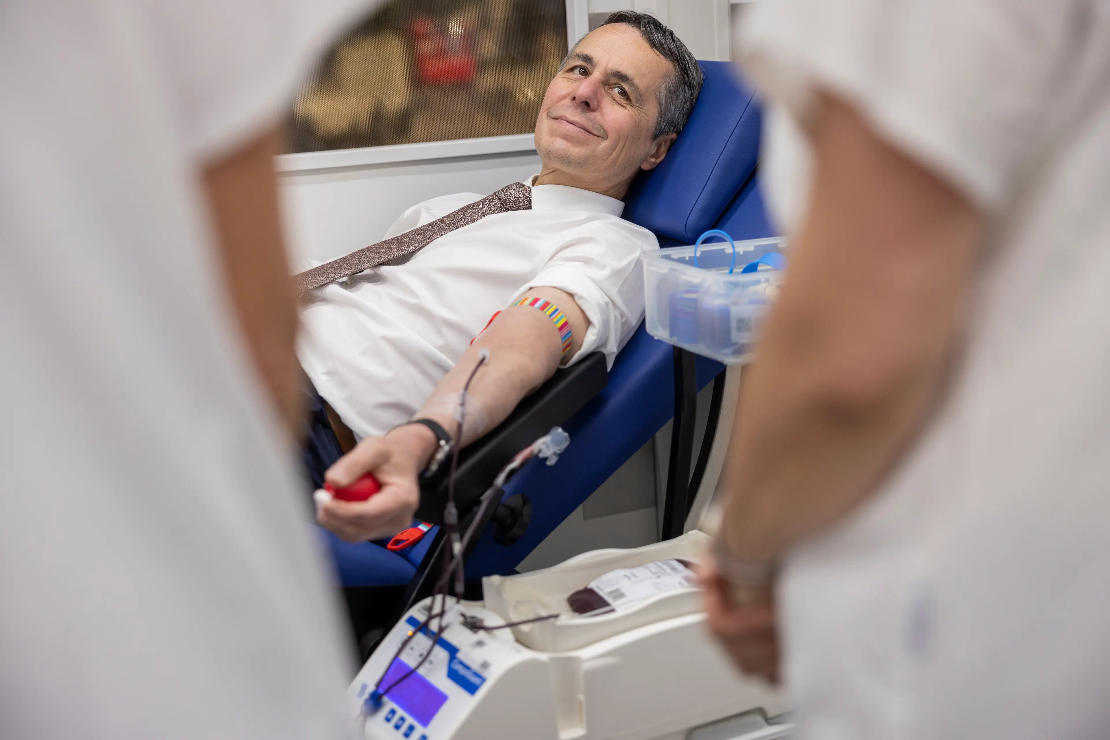 Federal Councillor Ignazio Cassis donating blood, lying in a recliner.