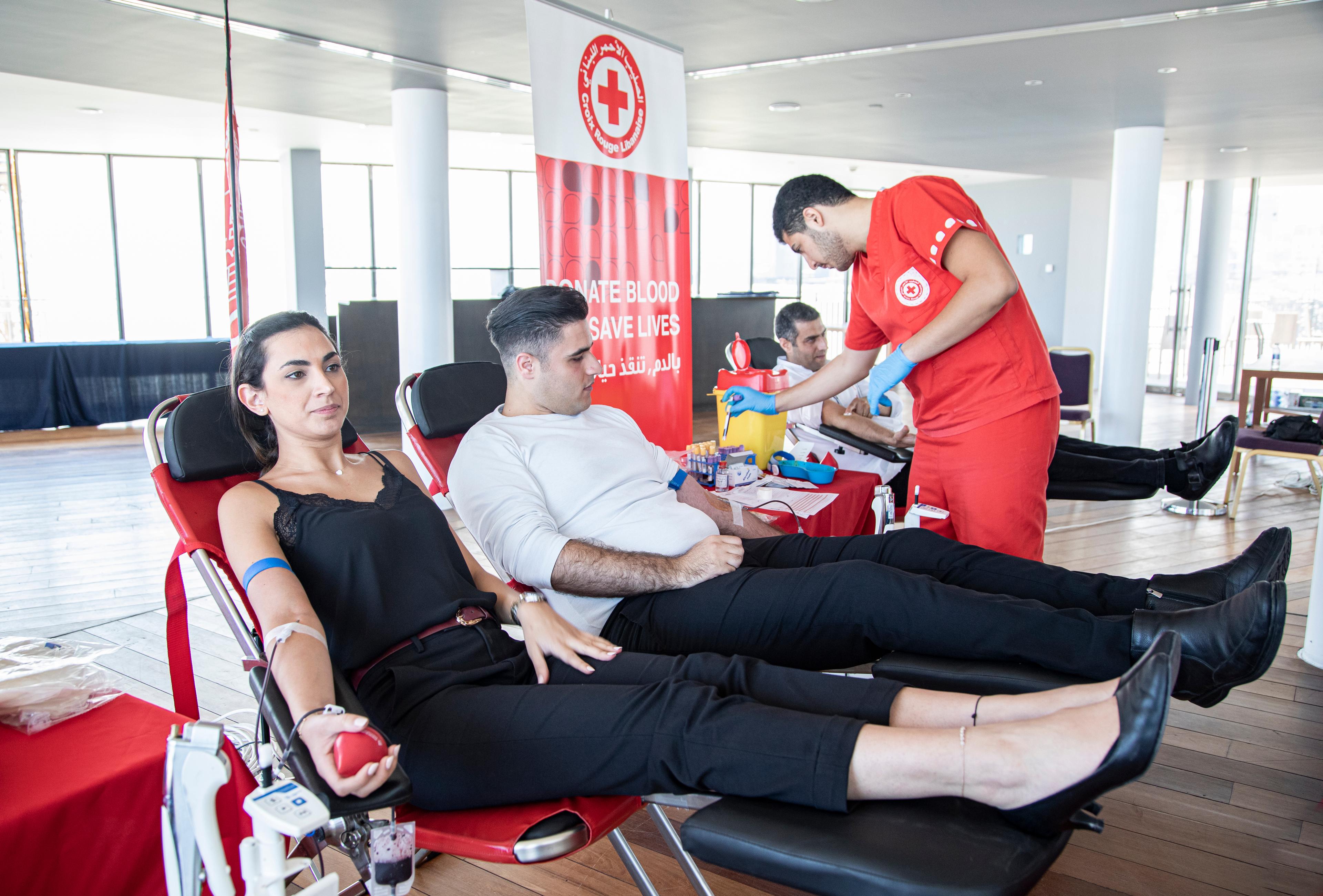 Three people donate blood at the Lebanese Red Cross. They are lying on reclining chairs.