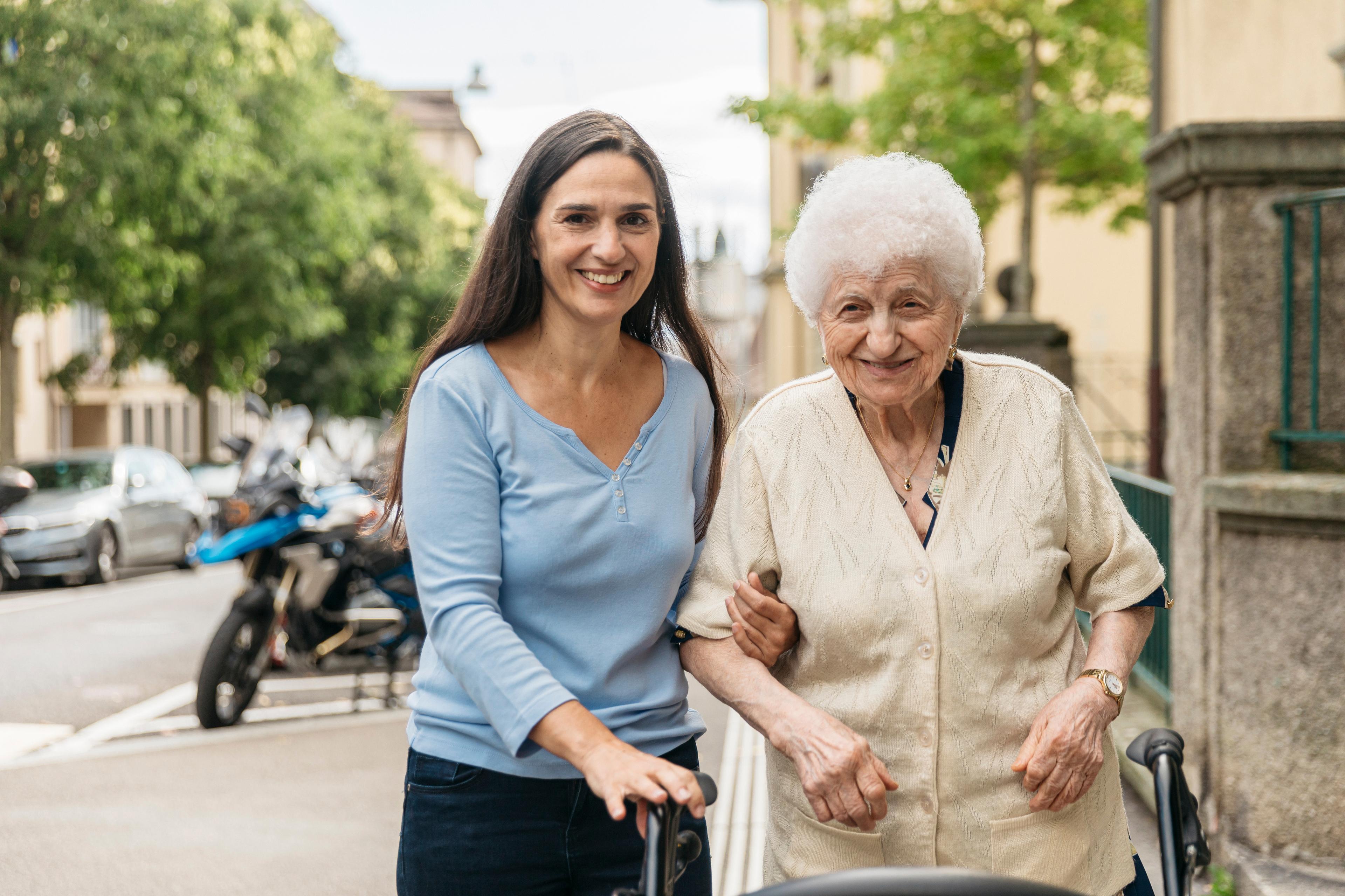 Una volontaria e una signora anziana fanno una passeggiata sotto casa.