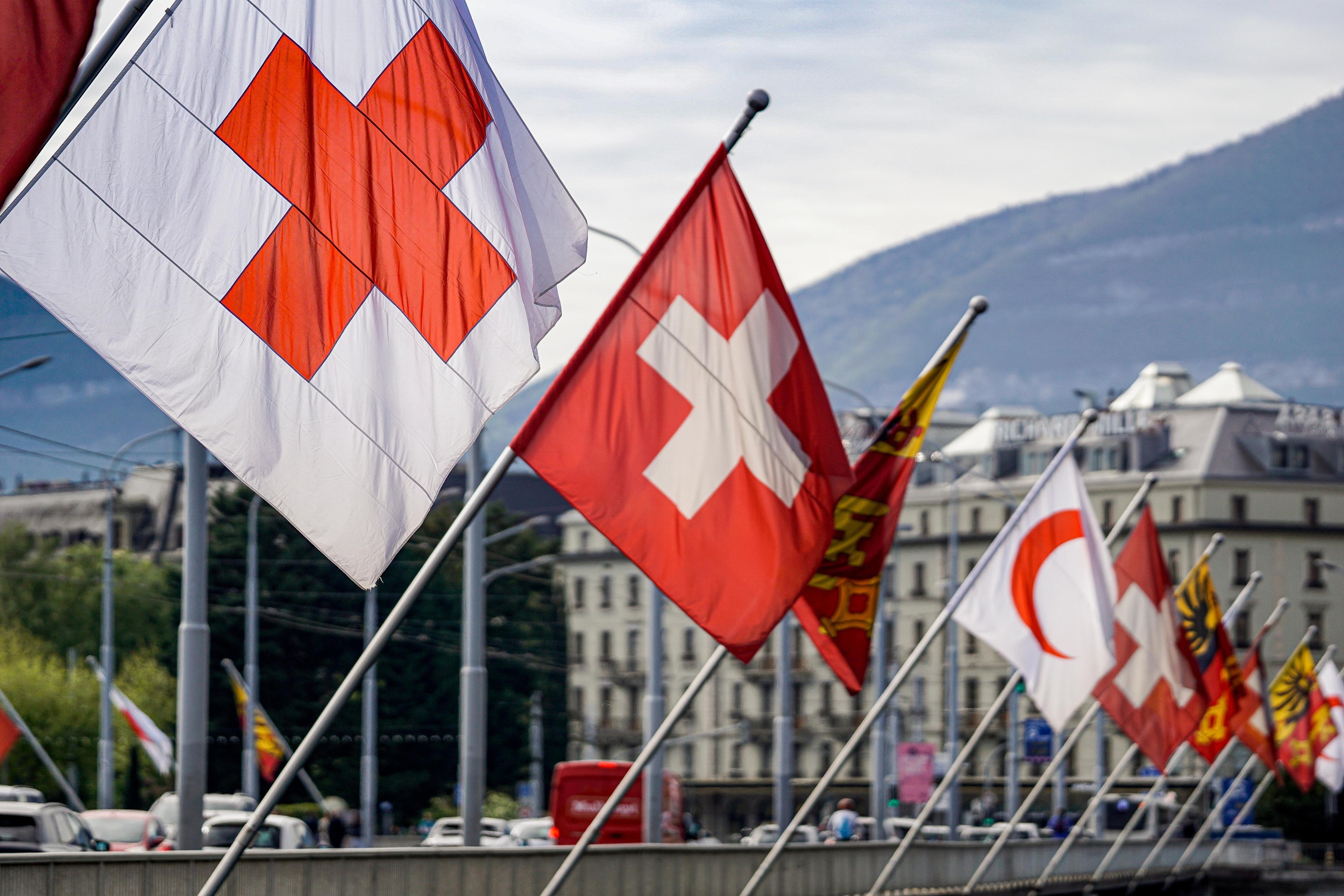 Divers drapeaux au bord du lac à Genève : la Croix-Rouge, le Croissant-Rouge, le drapeau suisse et le drapeau du canton de Genève.