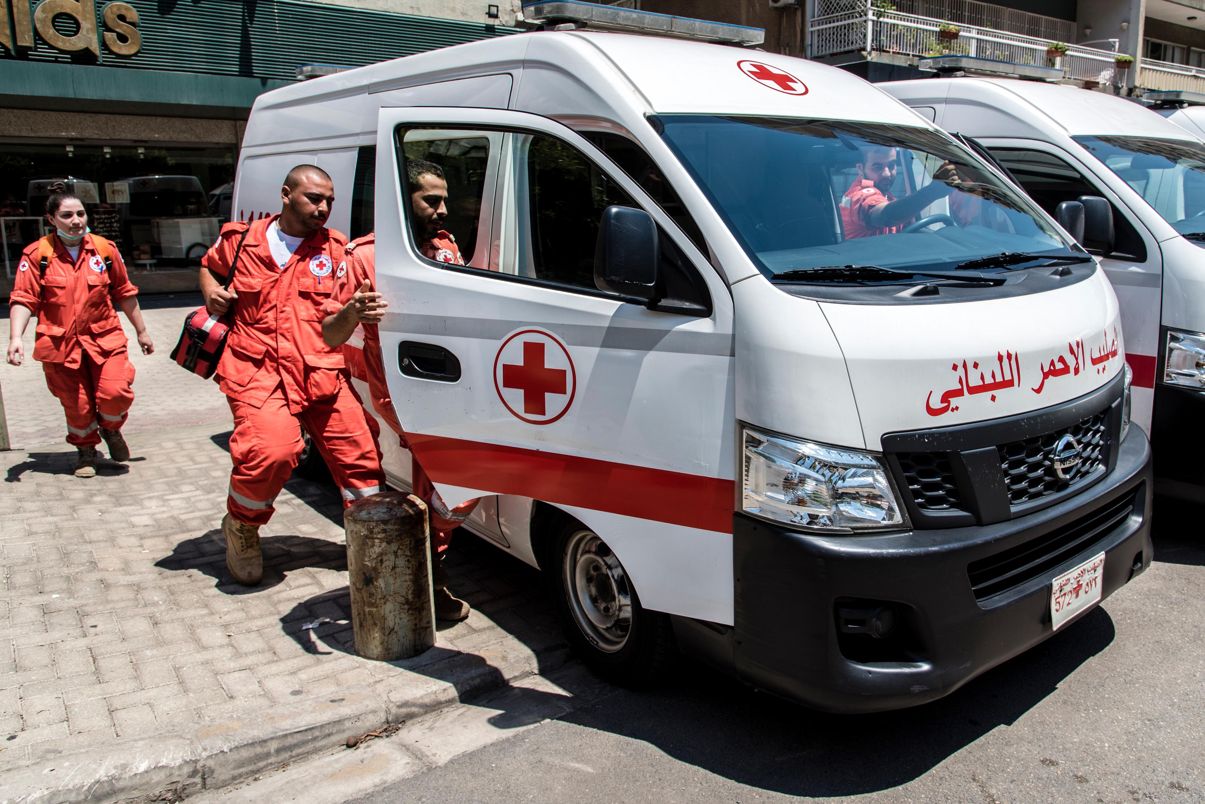 Tre uomini e una donna del servizio ambulanze della Croce Rossa libanese salgono sul loro veicolo di soccorso a Tripoli.