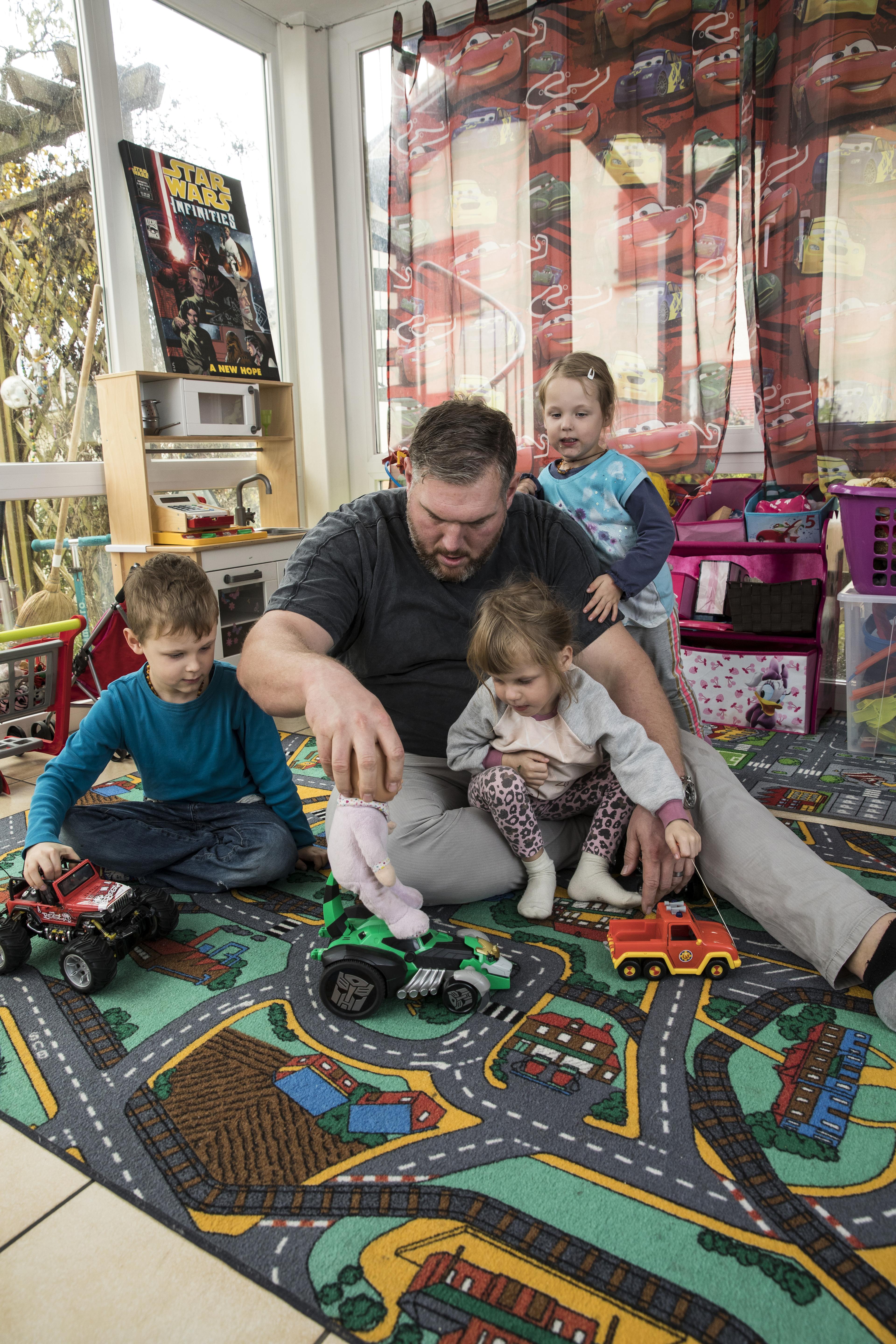 Christian Stucki, ambassadeur de la CRS, joue avec trois enfants assis par terre avec des voitures jouets.