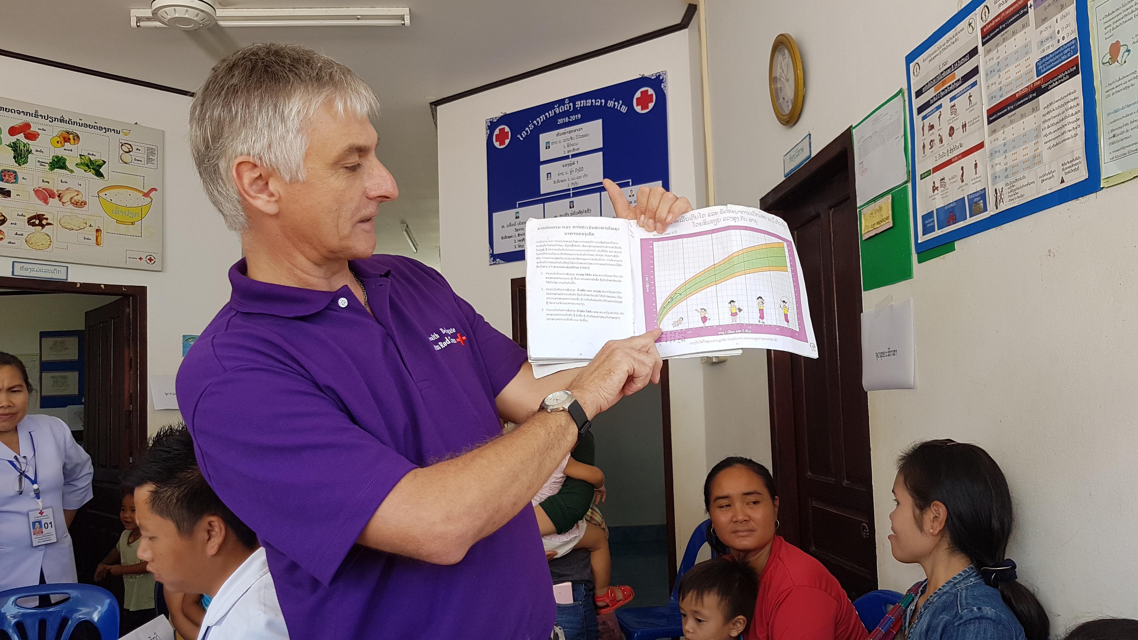 Dans la salle d’attente d’un centre de santé au Laos, un homme informe des femmes avec enfants en bas âge sur le développement de leurs petits.  
