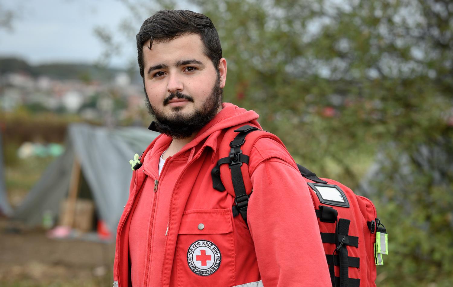 Un jeune homme portant un gilet de la Croix-Rouge polonaise regarde la caméra avec assurance.