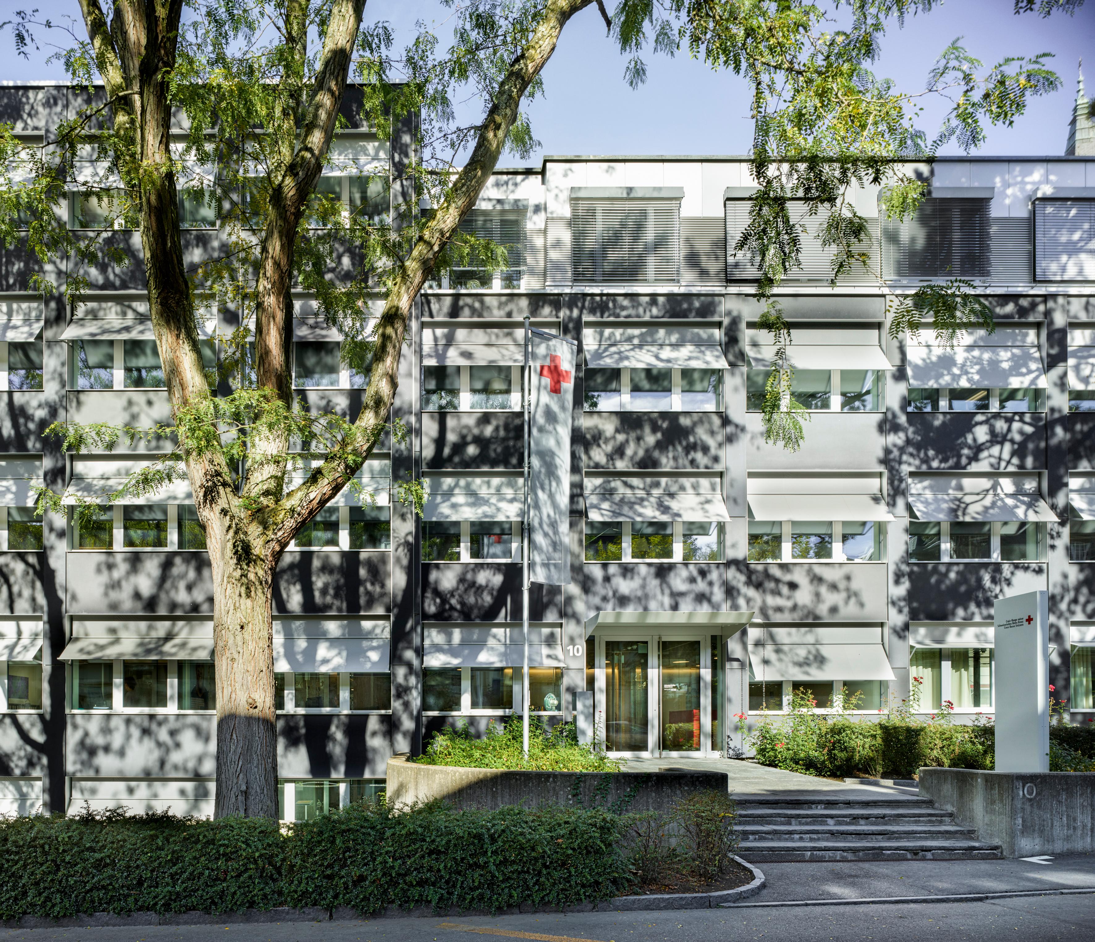 L'edificio della sede nazionale della CRS a Berna. Davanti ad esso c'è un albero e una piccola scala che conduce all'ingresso.
