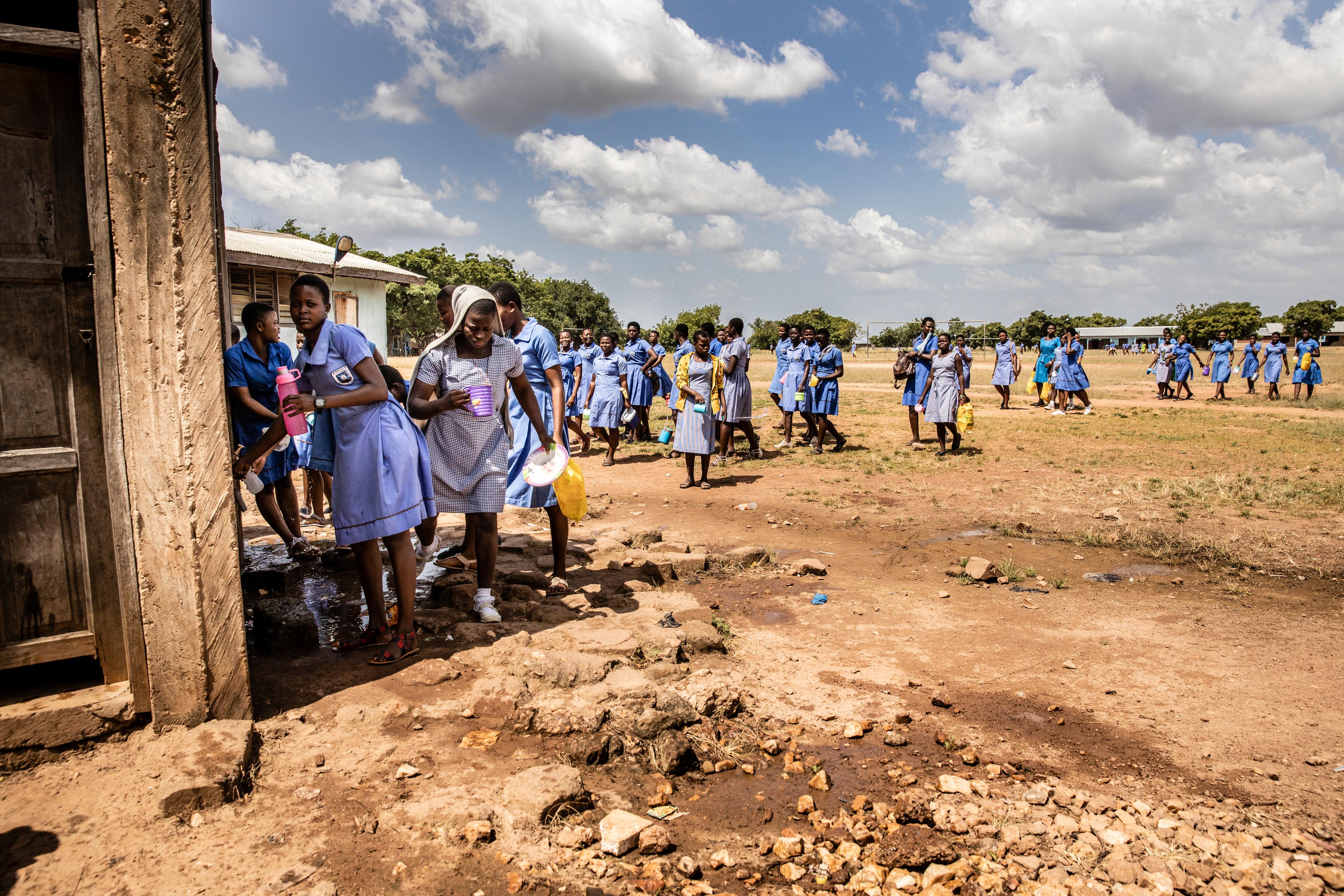 Schülerinnen und Schüler holen sich bei der Wasserstelle Wasser, das sie in Flaschen und sonstige Behälter abfüllen.
