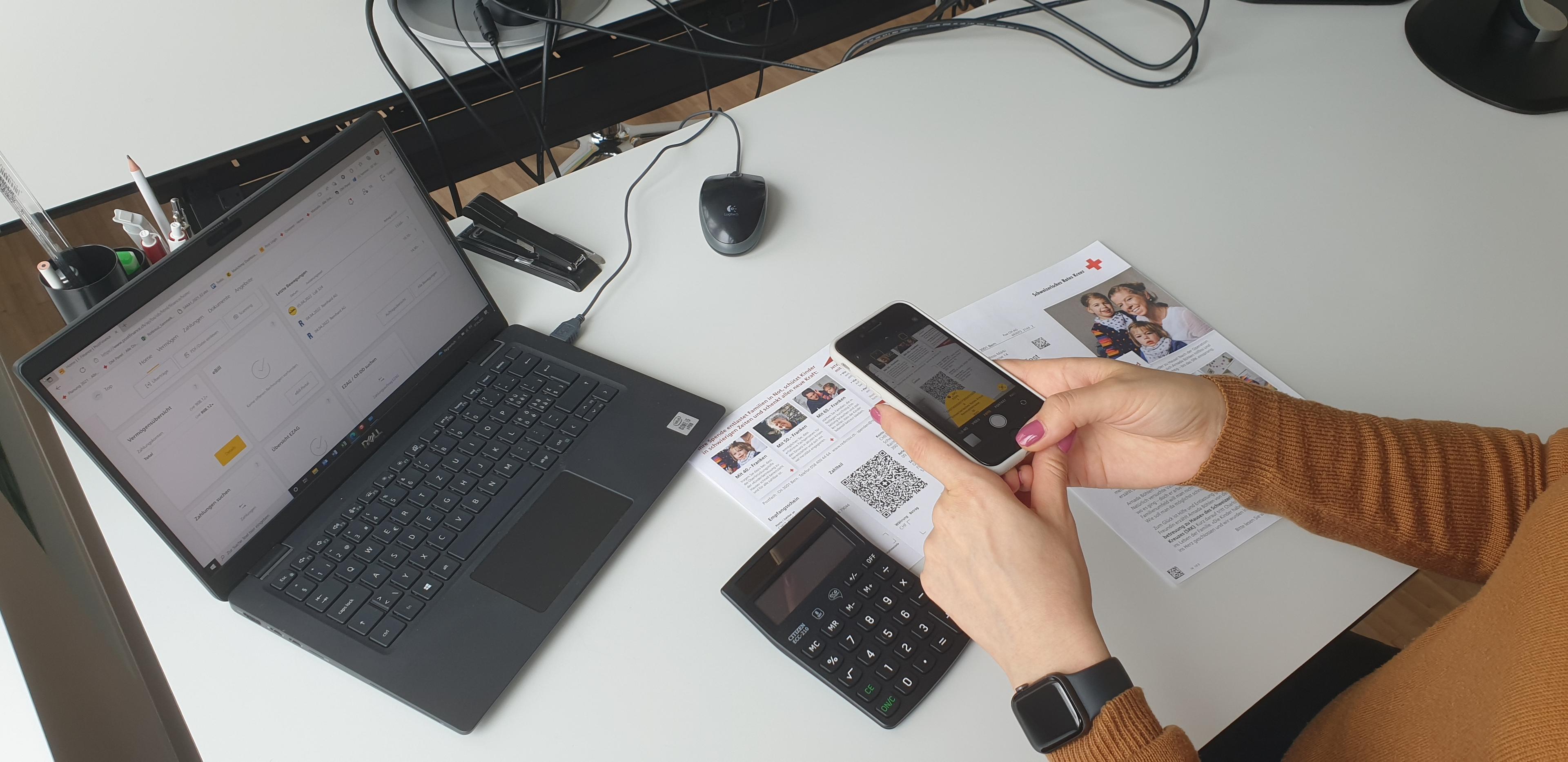 Eine Frau scannt den QR-Code auf dem Einzahlungsschein mit ihrem Smartphone.