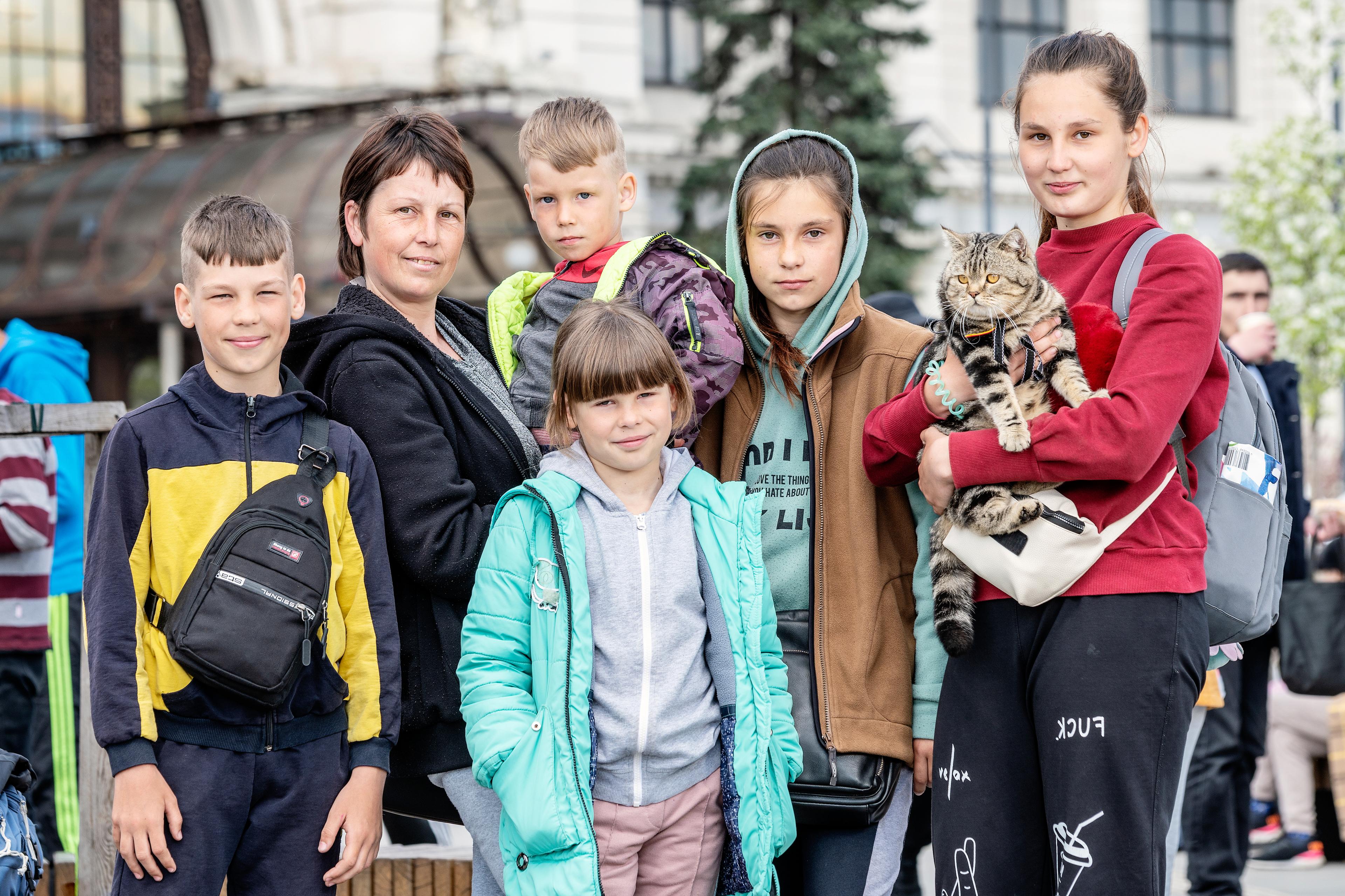 Photo de groupe de Luda Ostoparentsko avec ses cinq enfants et son chat. Ils regardent tous l'appareil photo, seul le chat s'en moque.