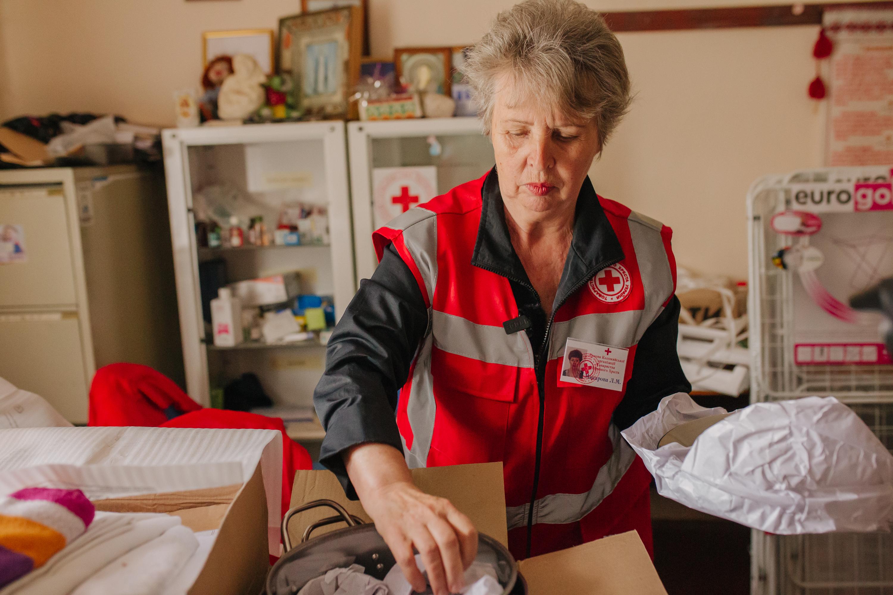Eine Mitarbeiterin des Ukrainischen Roten Kreuzes vor einer Hausapotheke. Sie scheint eine Tasche mit notwendigem Material vorzubereiten.